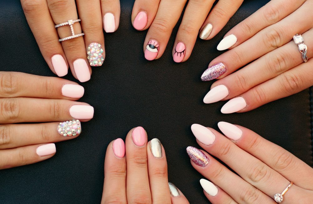 Close up of different fashionable and trendy manicure with design on girl s hands. Incognito female hands with elegance silver rings holding black leather hand bag. Concept of beauty and manicure.